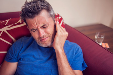 Man feels strong ear pain. People, healthcare and medicine concept