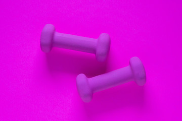Fitness equipment with womens purple weights/ dumbbells isolated on a purple background with copyspace