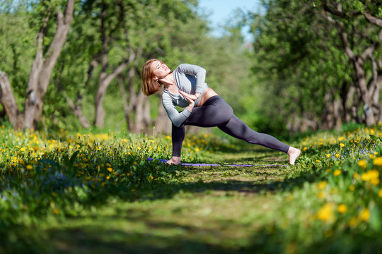 Image of woman with hands to side practicing yoga in forest