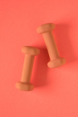 Fitness equipment with womens orange weights/ dumbbells isolated on a orange background with copyspace