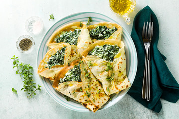 Traditional Italian pancakes crepes with spinach and ricotta on a served table. healthy vegetarian...