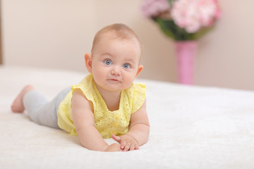 Beautiful and cute baby sitting on bed.