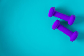 Fitness equipment with womens purple weights/ dumbbells isolated on a light sky blue background with copyspace