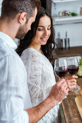 beautiful young couple clinking with glasses of red wine