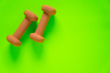 Fitness equipment with womens yellow orange weights/ dumbbells isolated on a lime green with copyspace background with copyspace
