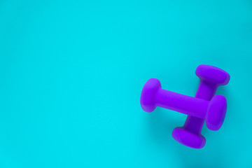 Fitness equipment with womens purple weights/ dumbbells isolated on a light sky blue background with copyspace