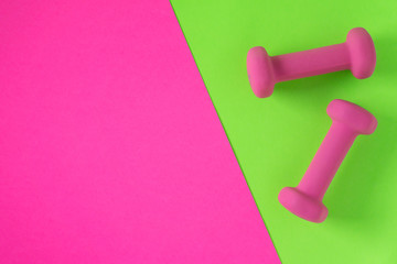 Fitness equipment with womens pink weights/ dumbbells isolated on a lime green and hot pink background with copyspace