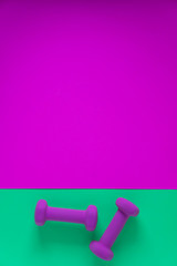 Fitness equipment with womens purple weights/ dumbbells isolated on a teal green background with copyspace
