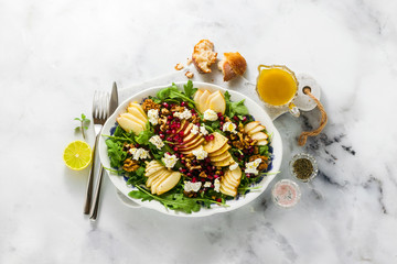 Fototapeta na wymiar Pomegranate & Pear Green Salad with Ginger Dressing on white marble . healthy breakfast or lunch
