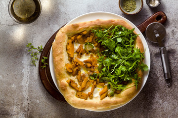 traditional Italian white pizza with taleggio cheese, caramelized pumpkin and arugula on the table