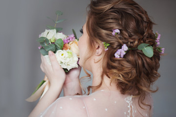 Obraz na płótnie Canvas Beautiful and elegant wedding hairstyle. Young bride with bouquet of flowers