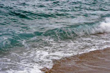 Spain, the clear water of the Mediterranean Sea, the wave rolling in the sand.