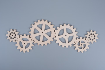 Gears assembled in a puzzle mechanism to work on a gray background. Business concept idea, partnership, cooperation, teamwork. - obrazy, fototapety, plakaty