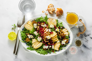 Pomegranate & Pear Green Salad with Ginger Dressing on white marble . healthy breakfast or lunch