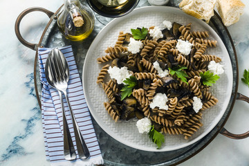 gluten-free pasta from half-wheat farro flour with portobello mushrooms and ricotta cheese on a tray on a marble table. healthy vegetarian recipes