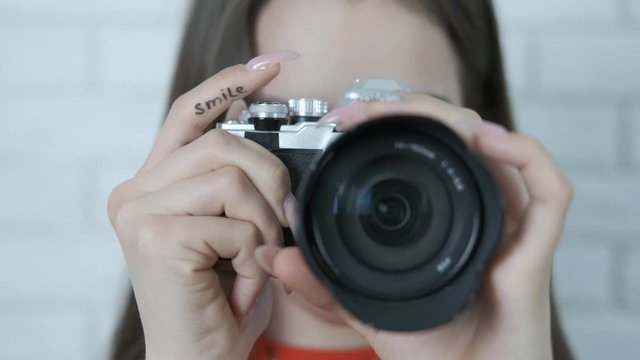 A female photographer asks for a smile. A young girl with a camera, with the inscription on her finger smile.