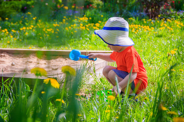A boy with a bucket and a shovel playing in the sand. Children's games. Summer and sand. The boy...