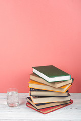 Book stacking. Open book, hardback books on wooden table and pink background. Back to school. Copy space for text.