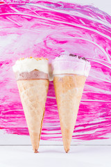 Melted ice cream with chocolate and nuts on a pink background. Two ice cream cones in pop art style. Summer milk dessert in a waffle cone. Summer concept