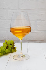 Glass of amber wine or orange wine on white background with grapes. Image with copy space.