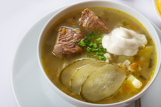Soup Rassolnik with pickled cucumber and sour cream on a white background. Russian cuisine. Close up. Selective focus. For the menu.