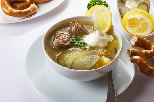 Soup Rassolnik with pickled cucumber, lemon and sour cream on a white background. Russian cuisine. Close up. Selective focus. For the menu.