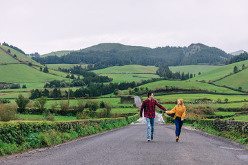 Obraz premium guy and girl holding hands and look at each other. mountains and