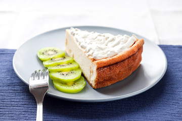 Homemade cottage cheese and semolina cake with kiwi fruit and cream on a plate