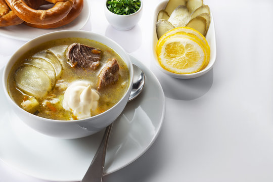 Soup Rassolnik with pickled cucumber and sour cream on a white background. Russian cuisine. Close up. Selective focus. For the menu.