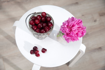 bouquet of the red peonies in a vase stands on a white chair in the interior