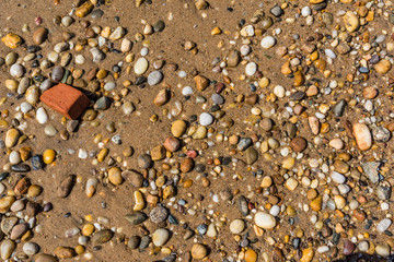 multitude of rocks and sand on a beach with a brick
