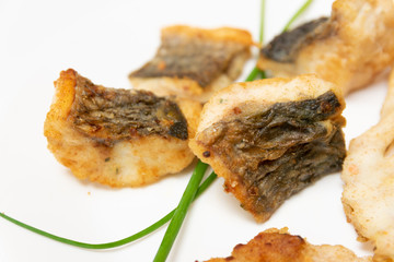 Tasty food, nutrition, kitchen and culinary concept: closeup pieces of fried, baked, golden and tasty fish on a white plate.