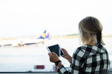 MAY 5 2016 - BUDAPEST, HUNGARY: woman looking at tablet and ryanair airplane at airport