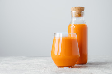 Fresh carrot juice in bottle with cork and glass, isolated over white background with copy space for your information. Healthy drinking concept