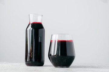Horizontal shot of two glass containers full of fresh beetroot juice, isolated on white background. Vitaminized drink made of vegetables