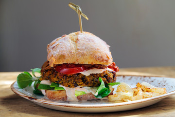 Vegetarian burger made from butternut squash and lentils with fried onion, greens and sun dried tomato paste
