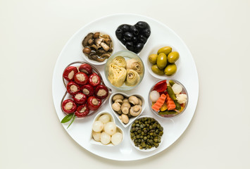 Italian traditional pickles on a plate. tuna stuffed peppers, artichokes in oil, olives, mushrooms, capers. copy space.