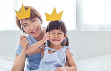 Portrait of mother and child daughter playing having fun together. Beautiful funny girl and mommy have crowns on sticks. Fun love family lifestyle single mom love mother’s day holiday concept - obrazy, fototapety, plakaty