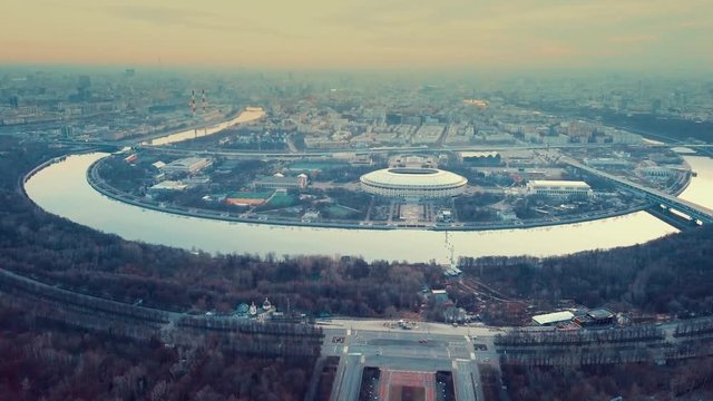 Early dawn in the city haze. Stadium and the bend of the river. Moscow from the air.