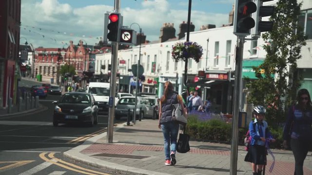 Girl in jeans and jacket with bags crossing a street in Dublin, Ireland.
