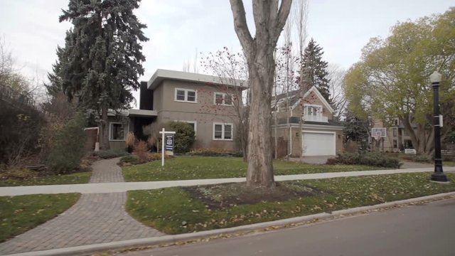 View down a street of an established neighbourhood with houses and large trees; Edmonton, Alberta, Canada