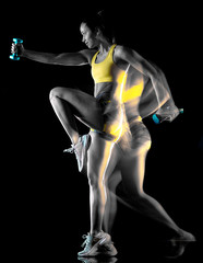 Fototapeta na wymiar one mixed race woman exercising fitness exercises isolated on black background with lightpainting effect multiple exposures