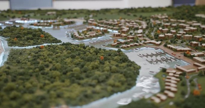 Architecture design studio with plastic model and mock-up of new buildings in city area. Close-up of urban development with houses, homes, marina, port, park and sea