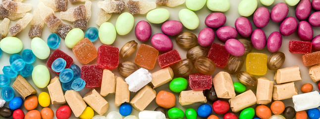 Fototapeta na wymiar banner of multicolored caramel candies scattered on the table background. sugar products. colored sweets