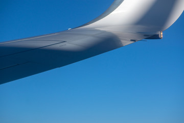 In-flight view on aircraft outer wing with blue sky background