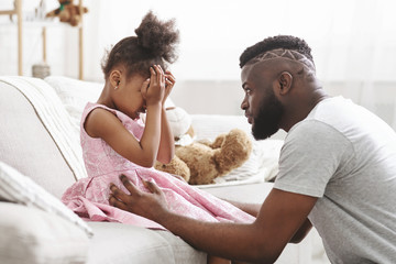 Loving african american dad comforting crying daughter