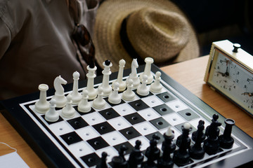A chess set with special holes for travelers and for the blind is on the table next to the clock,...