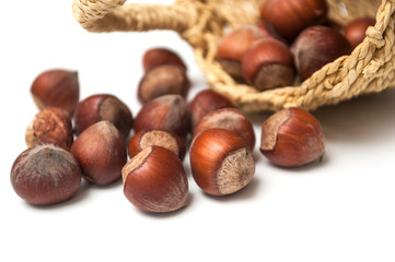 closeup of nuts falling from basket on white background