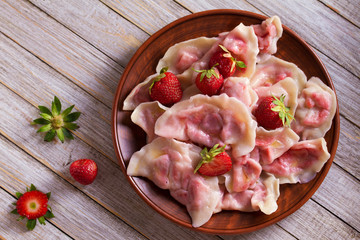 Dumplings, filled with strawberries. Varenyky, vareniki, pierogi, pyrohy - dumplings with filling. View from above, top studio shot