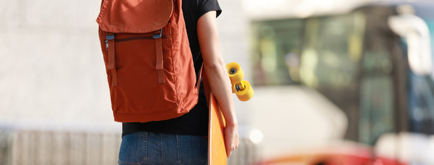 Woman walking with skateboard in hand on city street © lzf